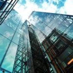 A striking view of a modern glass skyscraper reflecting the sky and clouds.